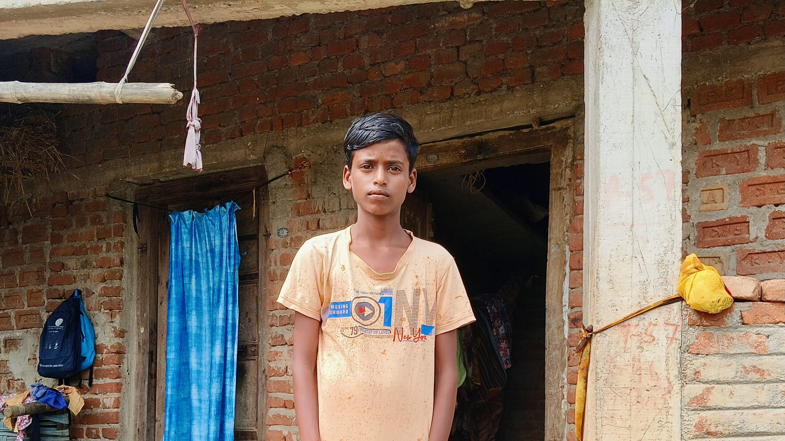 13-year-old child Sonu standing in front of his house